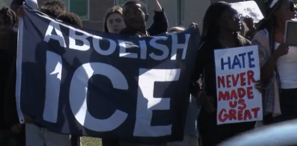 Students holding up a sign that says, "ABOLISH ICE" (right) and a student holds up a sign that states, "HATE NEVER MADE US GREAT" (left)